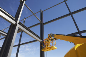 Welder working from cherry picker on warehouse construction